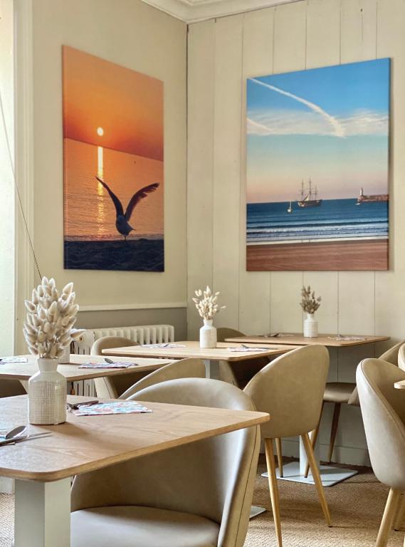 a restaurant with tables and chairs and paintings on the wall at Maison Richet in Les Sables-d'Olonne