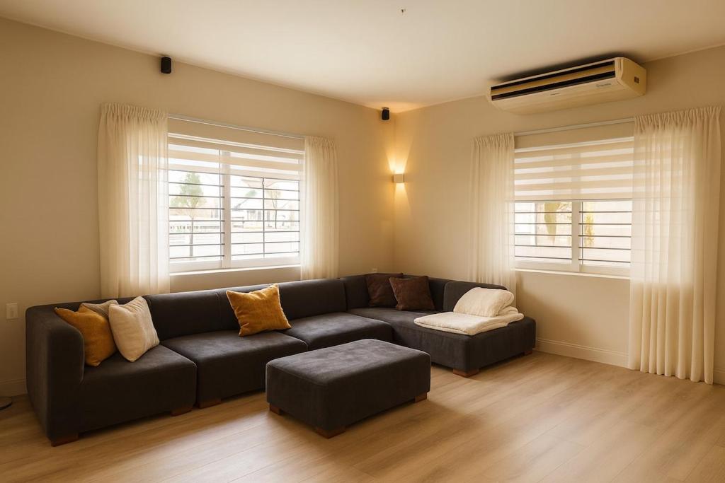 a living room with a couch and a ottoman at LUMA RESIDENCES - Premium Cozy 3-Bedroom Stay in Paramaribo