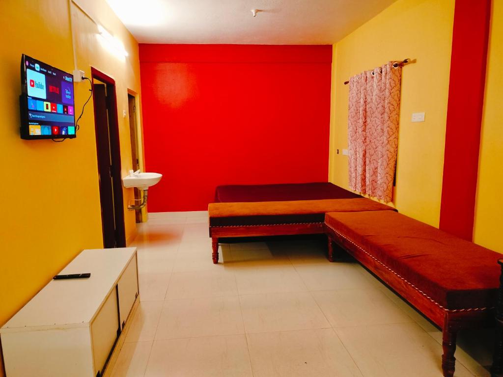 a room with two beds and a red wall at Harvest Hill View Cottage in Ooty