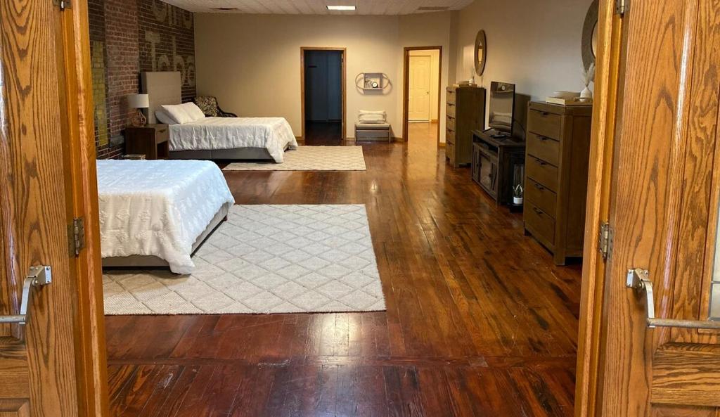 1 Schlafzimmer mit 2 Betten und Holzboden in der Unterkunft The Loft at Bite Me BBQ in Wichita