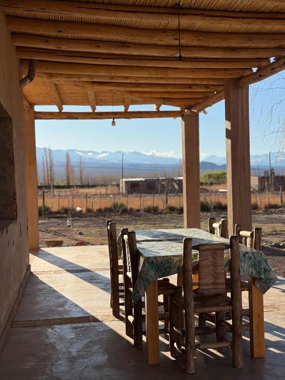 a wooden table and chairs on a porch with a view at Rancho Raíz in Barreal