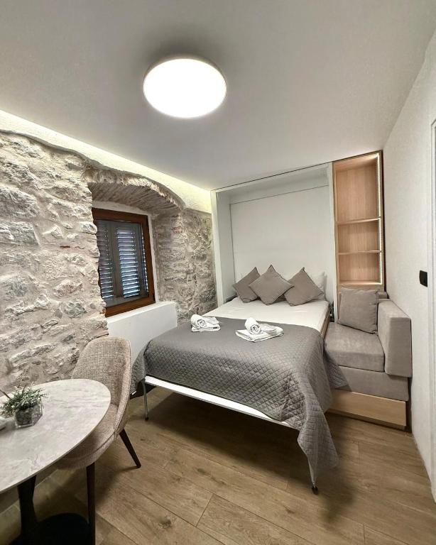 a bedroom with a bed and a stone wall at Casa Del Sol Pietra Kotor in Kotor
