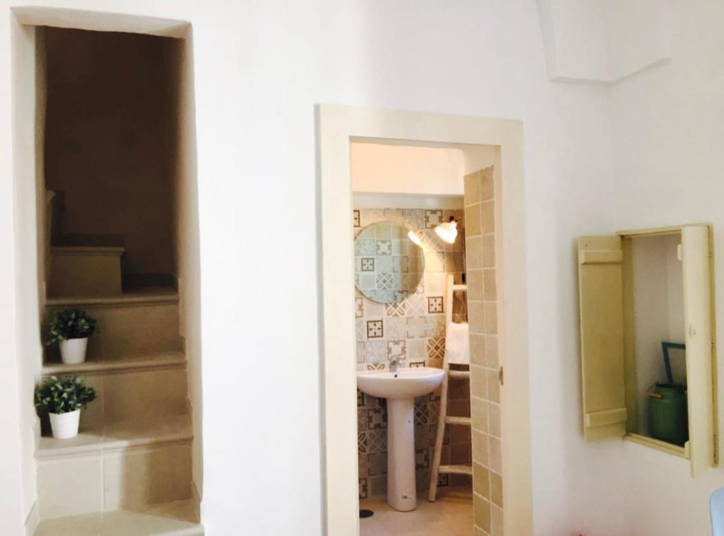 a white bathroom with a sink and a mirror at L'alcova di Garibaldi in Ostuni