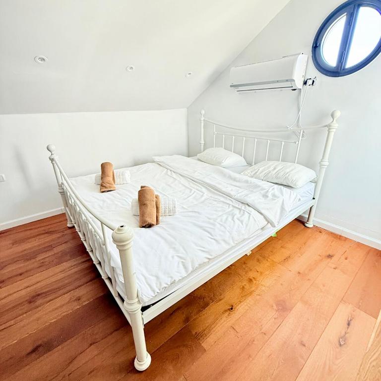 a white bed in a room with a wooden floor at Royal Retreat 6 Luxury Suites Villa & Pool in Herzliyya B