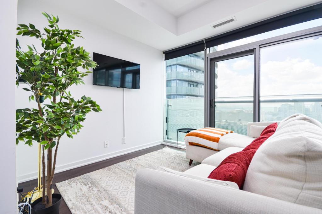 トロントにあるDowntown Toronto Condo CN Towerの白い家具と大きな窓のあるリビングルーム