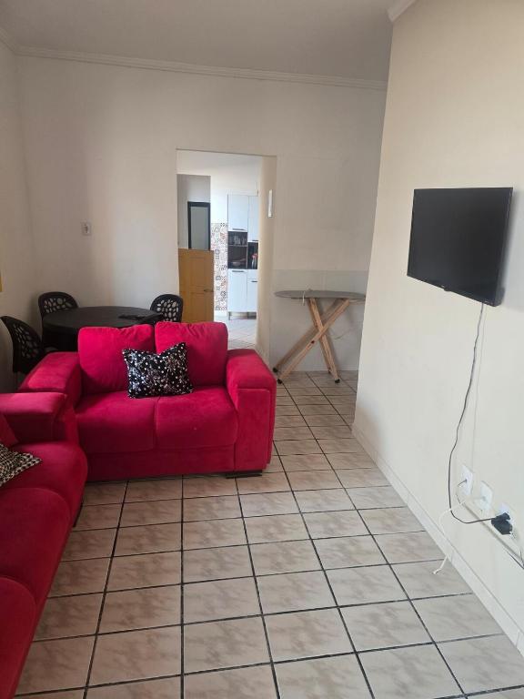 a living room with a red couch and a tv at Casa Pequena e agradável em Ilhéus in Ilhéus