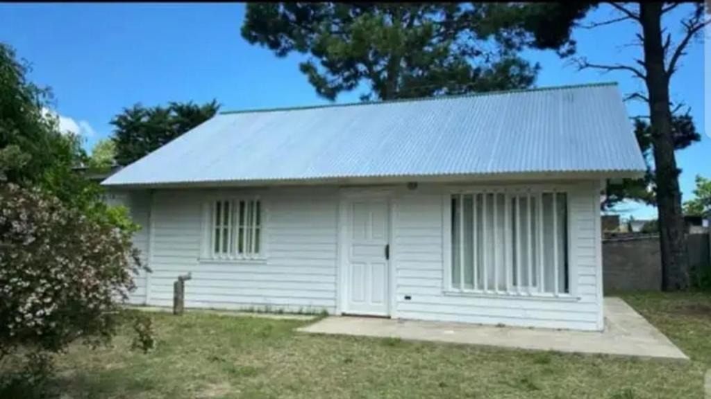 una pequeña casa blanca con techo en Cabaña en gesell, en Villa Gesell