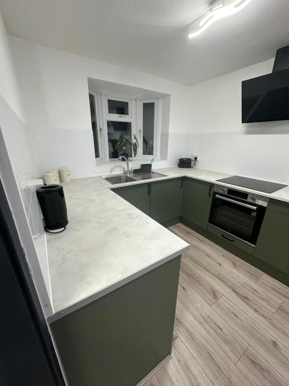 a kitchen with green cabinets and a white counter top at Adult only, fetish retreat play space in Ifield