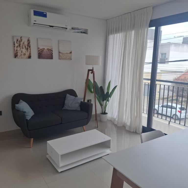 a living room with a blue couch and a balcony at LaFaldaStayBahia - Confort y Bienestar garantizado in Bahía Blanca