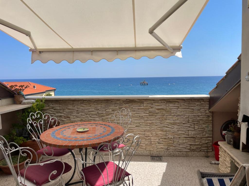 Un patio con mesa y sillas y el mar. en Splendida mansarda sul mare, en Savona