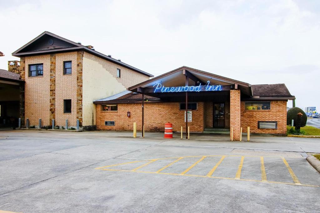a large brick building with a sign on it at OYO Pinewood Inn & Suites Silsbee in Silsbee