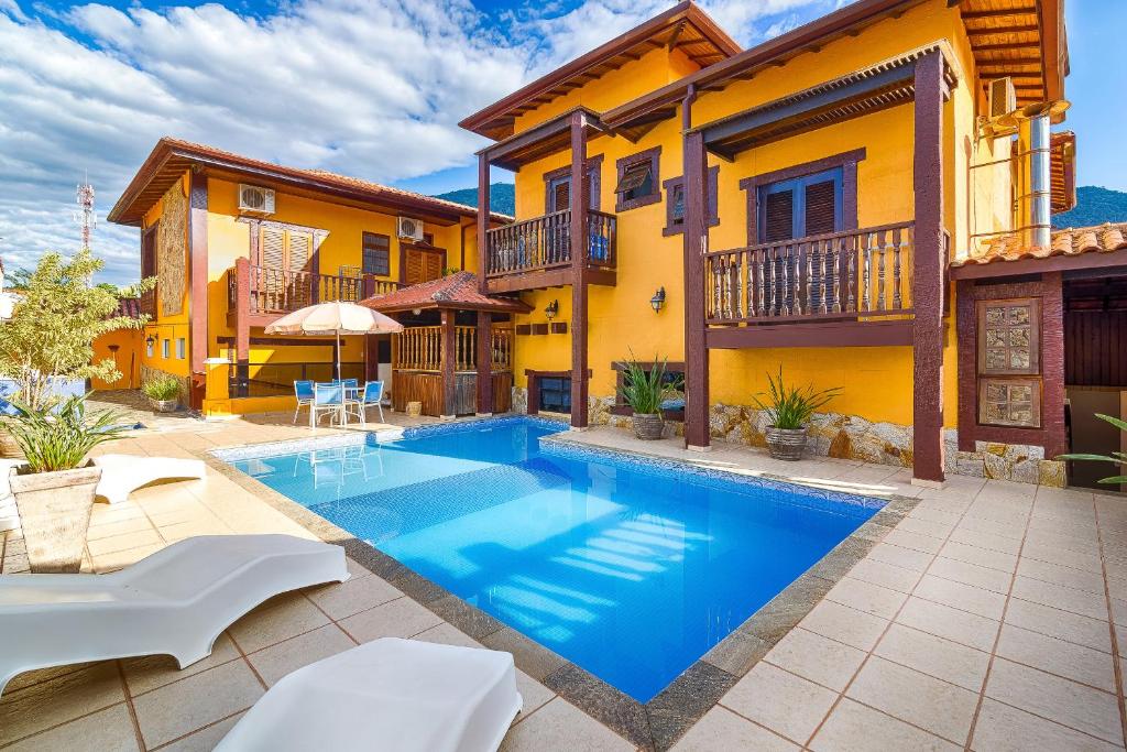 a swimming pool in front of a house at Aldeia Da Lagoinha in Ubatuba