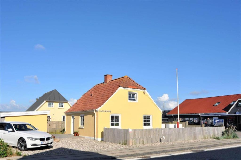 a white car parked in front of a yellow house at 70240-Ulfborg-Vesterhavsgade-12 in Thorsminde