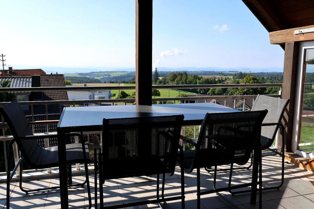 a table and chairs on a balcony with a view at Ferienwohnung in Strittberg mit Sauna und Alpenblick in Höchenschwand
