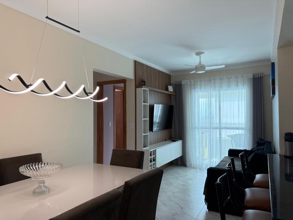 - un salon avec une table à manger et des chaises dans l'établissement Apartamento Vista Mar Mirim 2 Dormitorios suite com Wifi para até 8 pessoas 1 vaga de estacionamento, à Praia Grande
