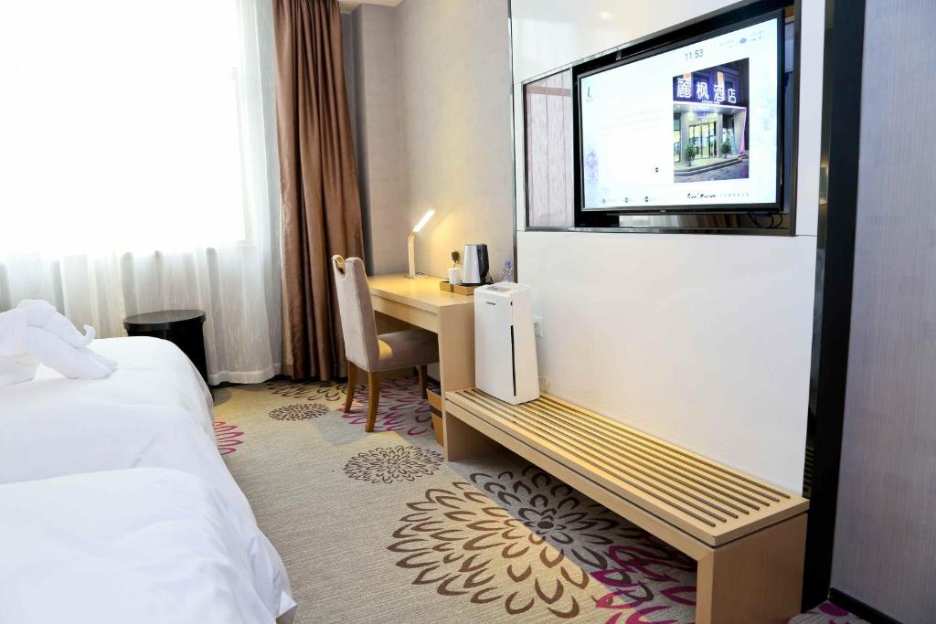 a hotel room with a bed and a desk with a television at Lavande Hotel Baiyun International Airport Branch in Guangzhou