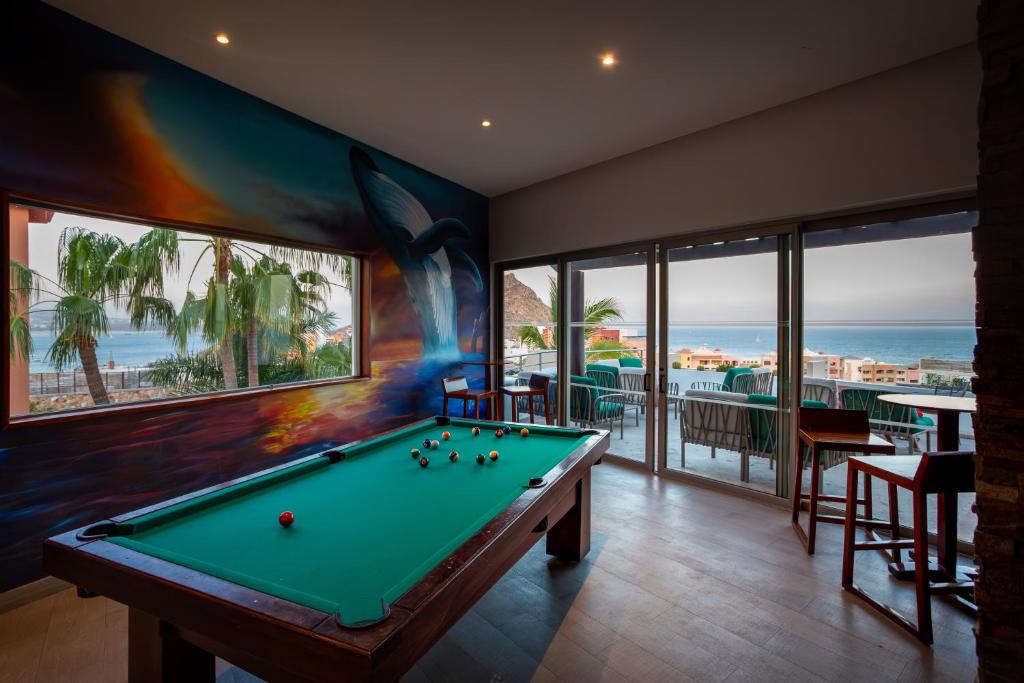 Recreation room with billiards table, ocean view windows, and coastal landscape visible through glass doors.