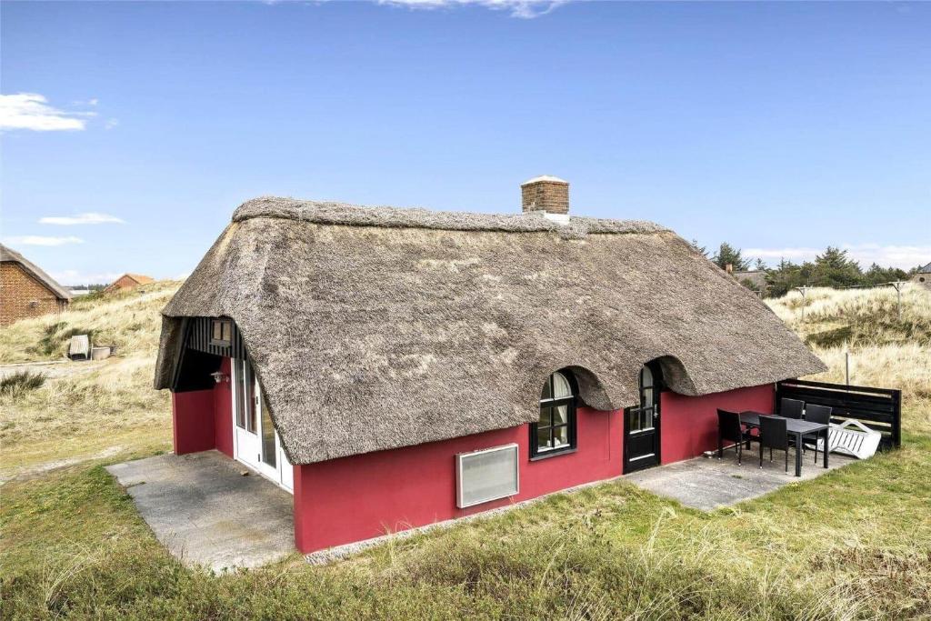 a red house with a thatched roof on a field at 20261-Ulfborg-Vederso-Klitvej-20 in Ulfborg