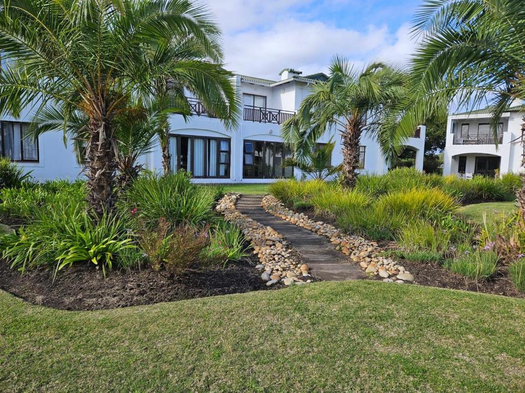 a white house with palm trees and a walkway at Keurbooms River in Keurboomstrand