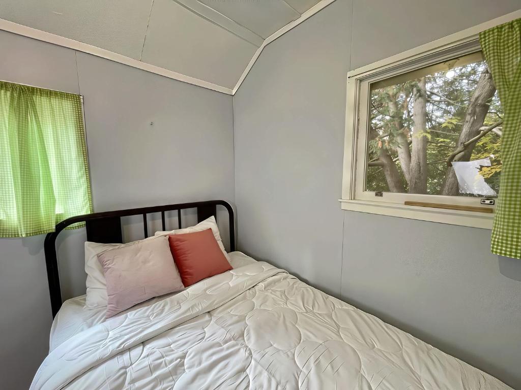 Un dormitorio pequeño con una cama y una ventana. en Ambleside - 2-Bedroom Cottage #5, en Kawartha Lakes