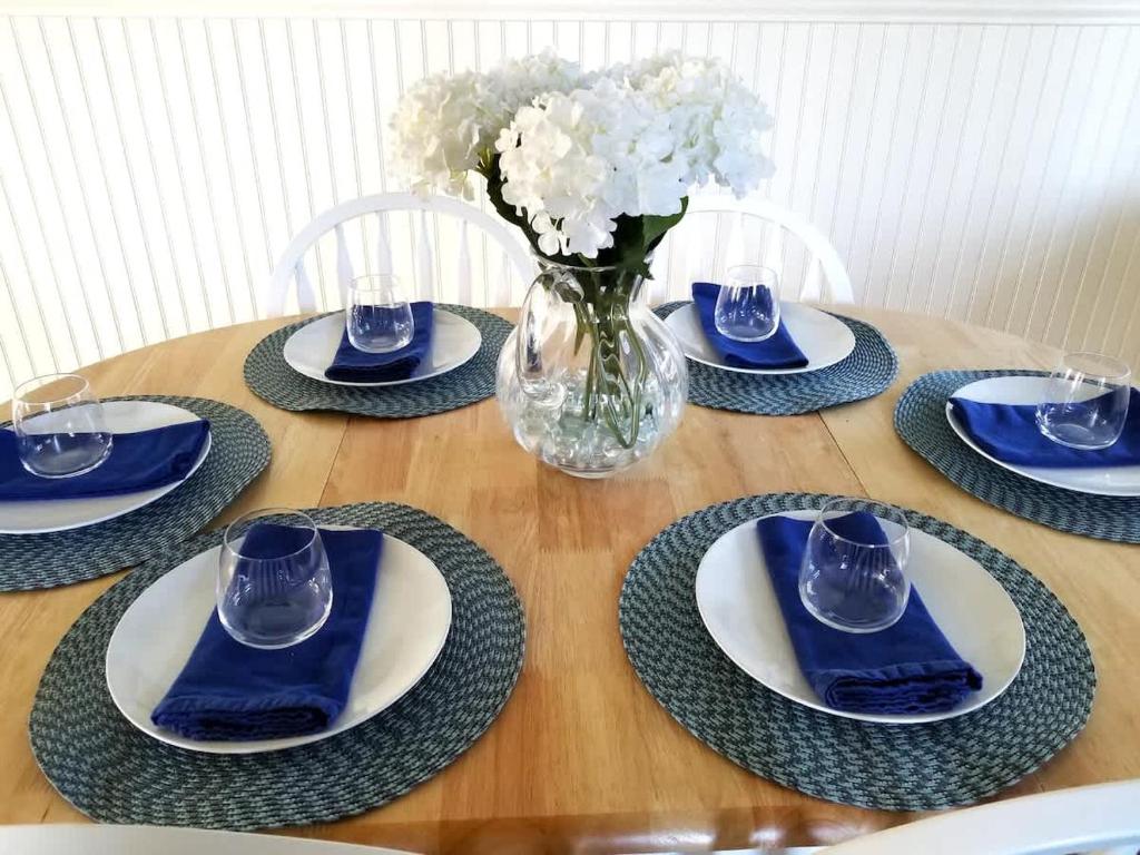 einen Tisch mit blauen und weißen Platten und eine Vase mit Blumen in der Unterkunft Spruce Beach Cottage - Walk to beach in Aptos