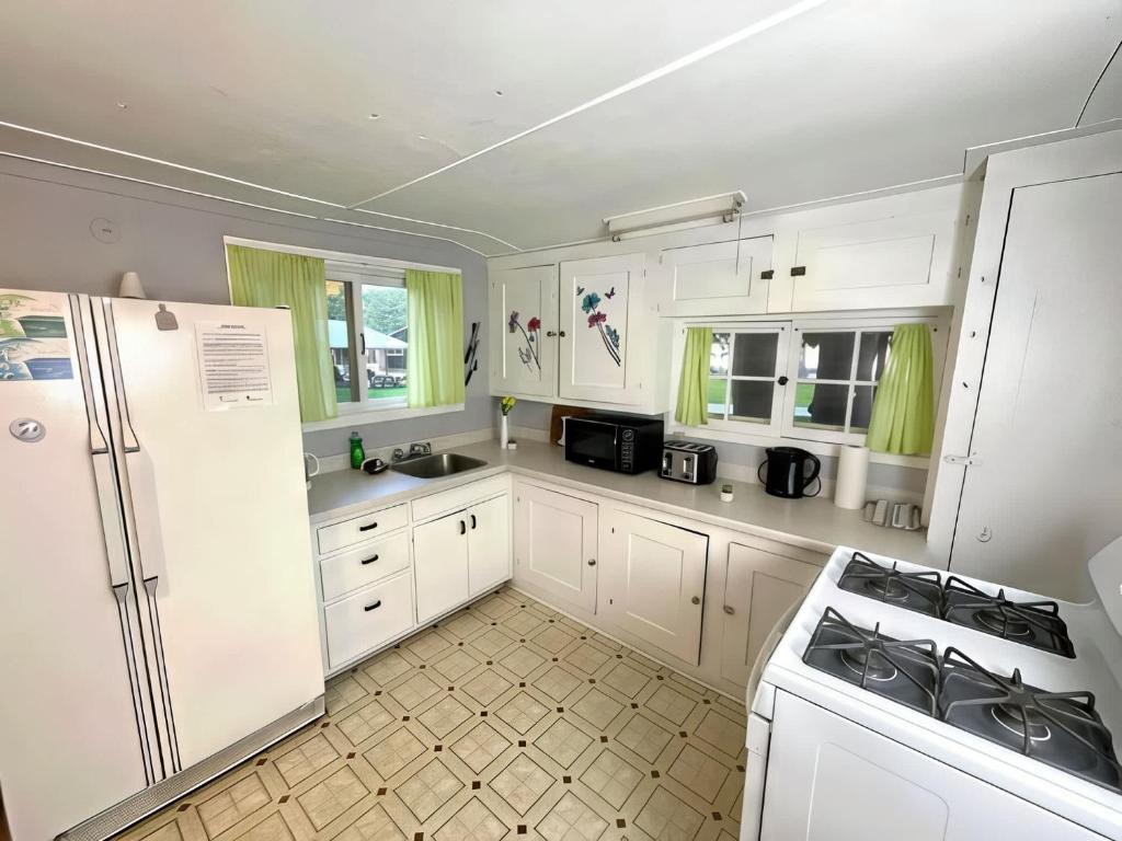 3-Bedroom Cottage #7 - Ambleside في كاوارثا ليك: مطبخ بخزائن بيضاء وثلاجة بيضاء