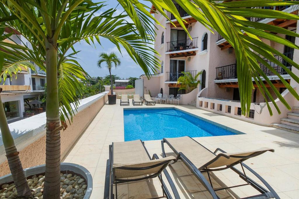 a villa with a swimming pool and a palm tree at Colonial Beach Apartment and 5th Floor in Playa del Carmen