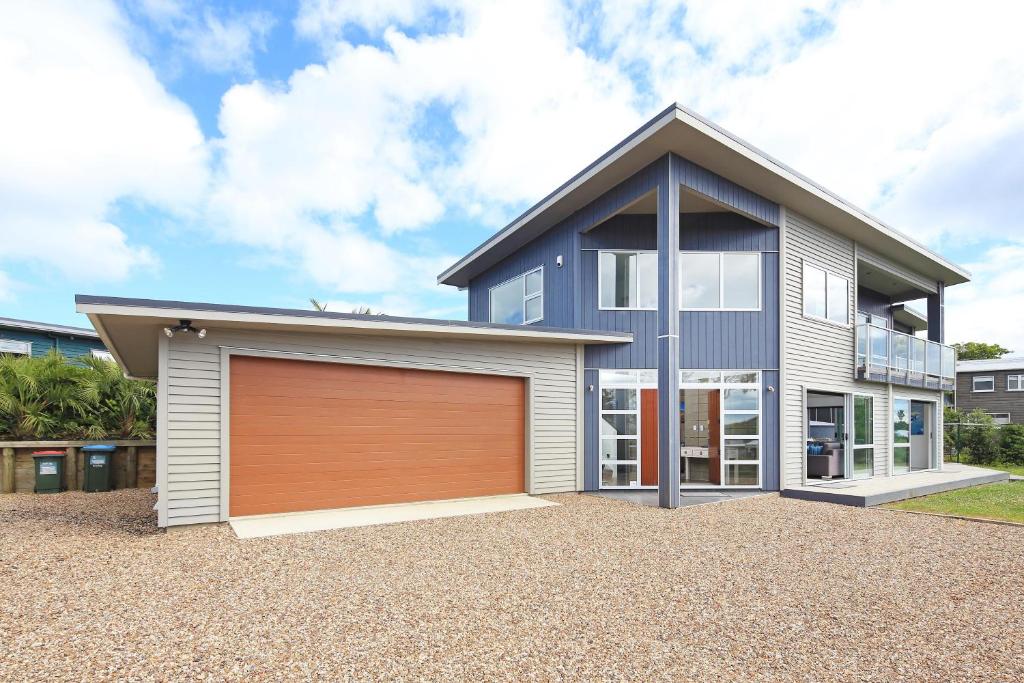 a house with a garage in front of it at Bella Seven- Waiheke Escapes in Oneroa