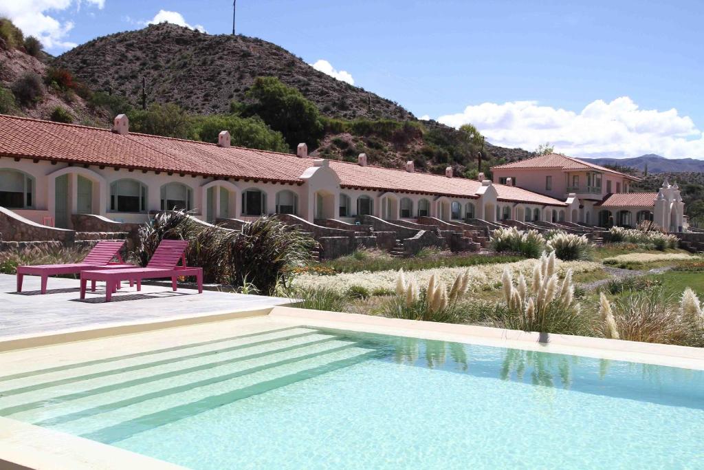 Hotel Huacalera في هواكاليرا: منزل به مسبح وكرسيين ورديين