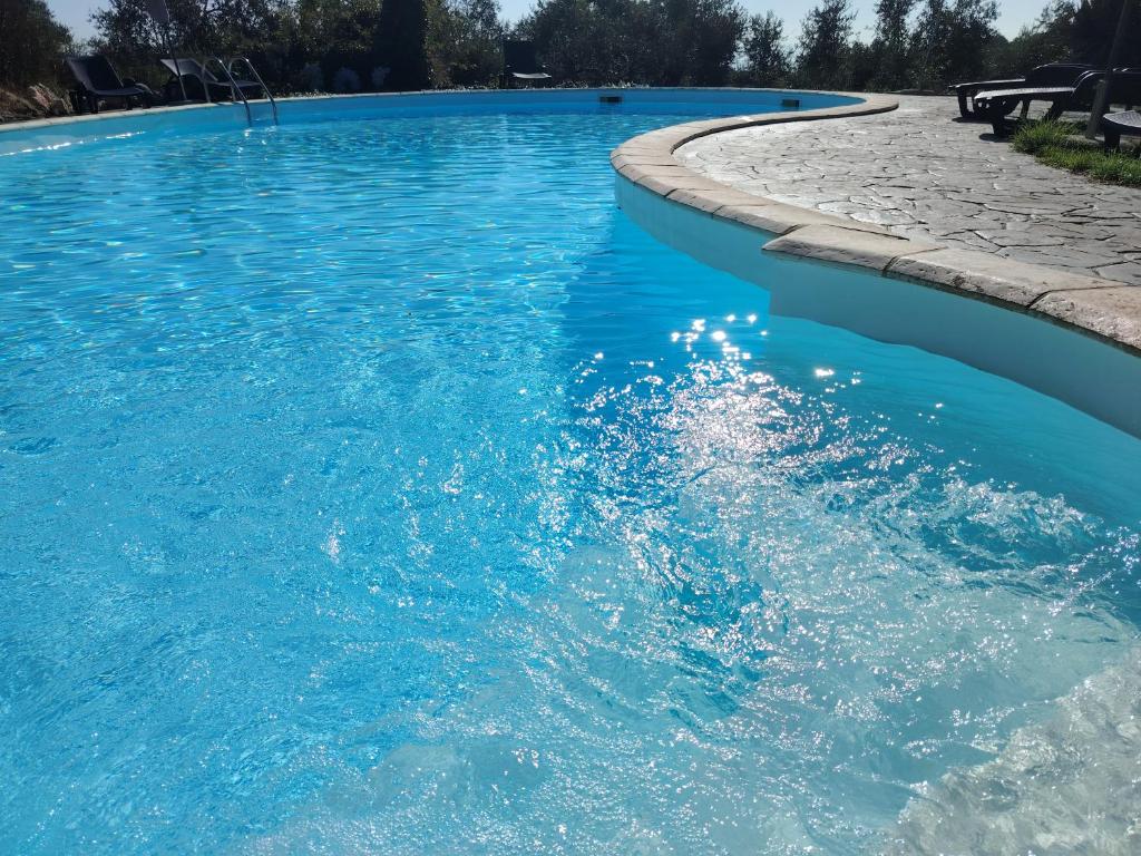 a swimming pool with blue water and a sidewalk at Agriturismo Corte Sakura in Montefiascone