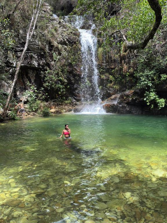 a person in the water in front of a waterfall at Pousada Loquinhas in Alto Paraíso de Goiás