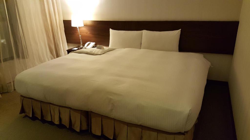 uma grande cama branca num quarto de hotel em Berkeley Business Hotel Zhongzheng em Hsinchu