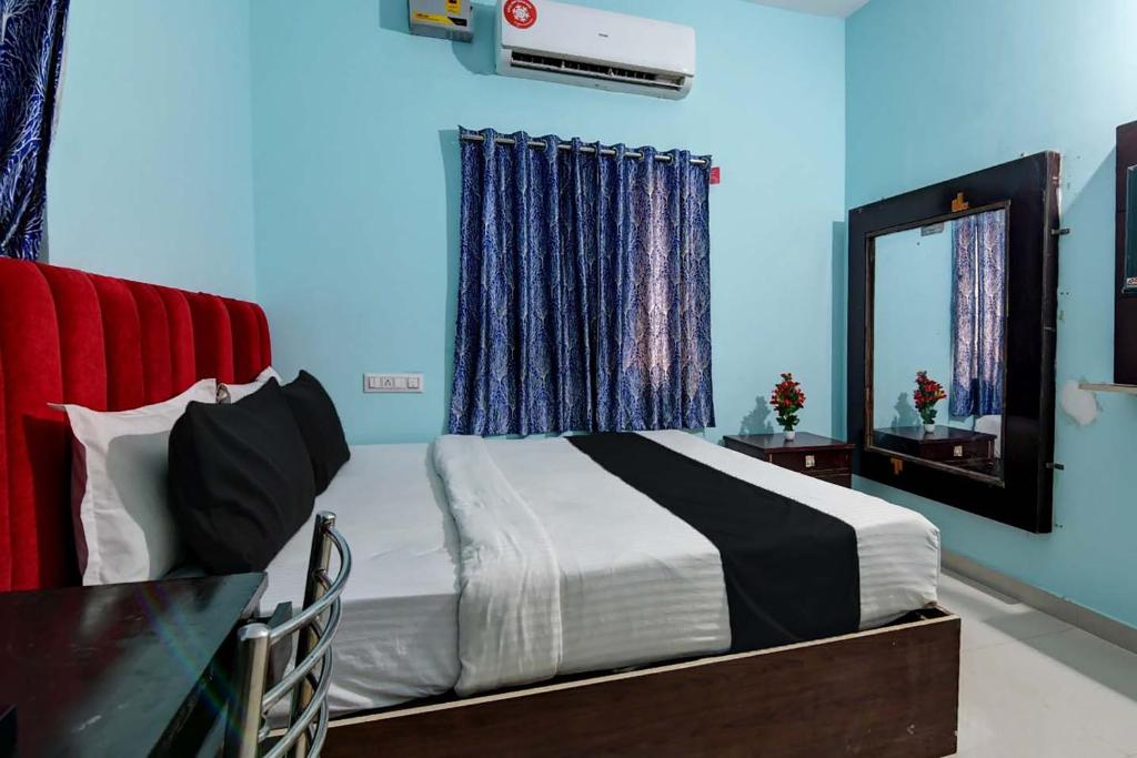 1 dormitorio con 1 cama con paredes azules y espejo en Hotel O AMULYA AASHIYANA, en Bhubaneshwar
