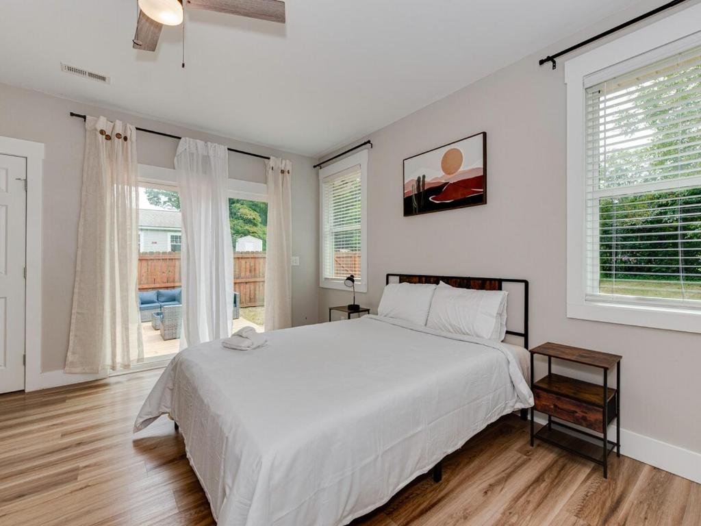 a white bedroom with a large bed and windows at Charlotte 5 Bedroom Home with Hot Tub, Patio, TV and Board Games Close to Uptown, Airport, Dining and Entertainment - Spacious Family Friendly! in Charlotte