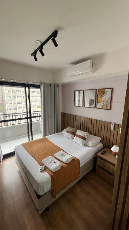 a bedroom with a large bed and a large window at Studio 604 - Seu refúgio Urbano no Coração de São Paulo - Wifi, Vaga, Academia, Lavanderia, Mercado e Rooftop in Sao Paulo