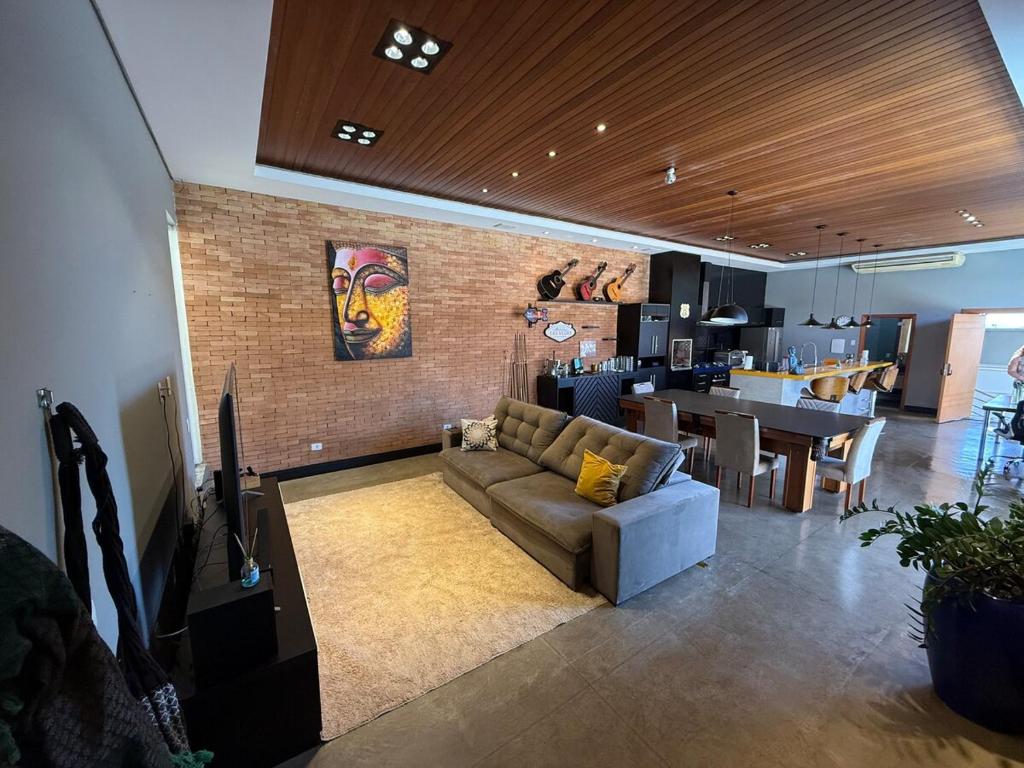 a living room with a couch and a dining room at Oka Tupis - casa de luxo para executivos c sauna e piscina aquecida in Santa Bárbara dʼOeste