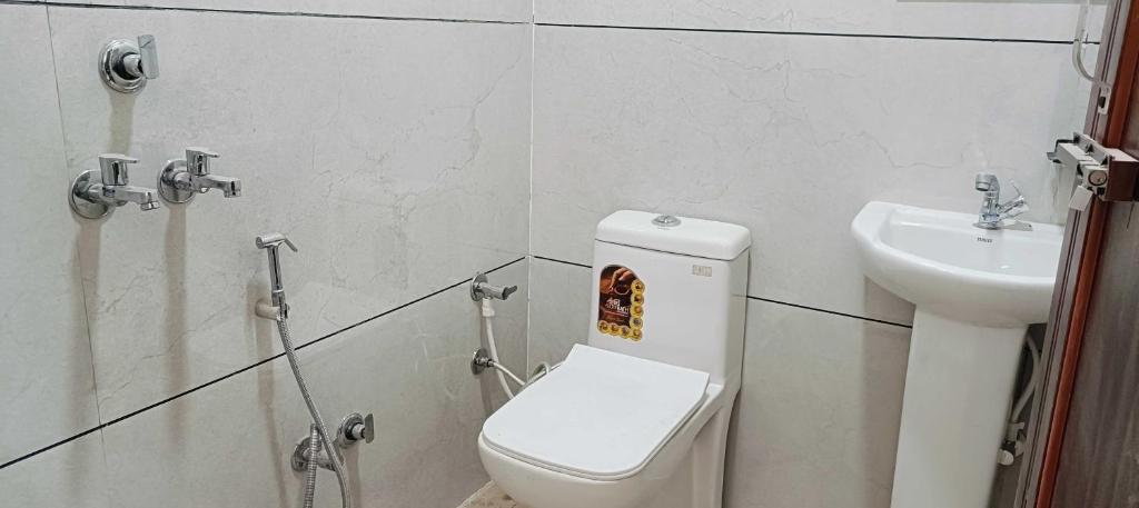 a bathroom with a toilet and a sink at Hotel O Sky Inn in Hānsi