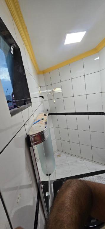 a white tiled bathroom with a sink and a mirror at Linda Casa 3 suítes in Belém