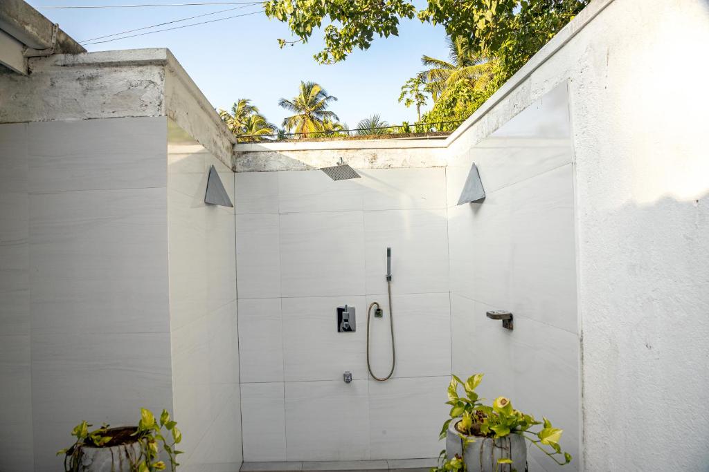 een witte badkamer met een douche en twee planten bij JA Retreat - Talpe in Talpe