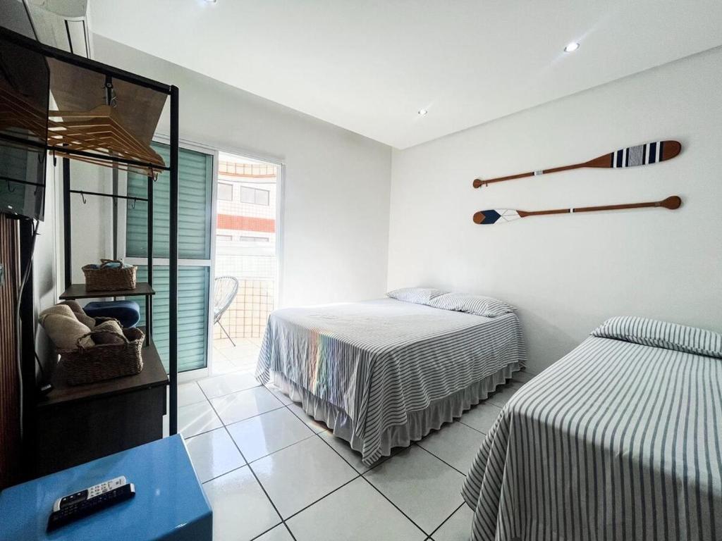 a bedroom with two beds and a tv in it at Onda76 Ap temporada Praia Grande Beira Mar churrasqueira carvão in Praia Grande