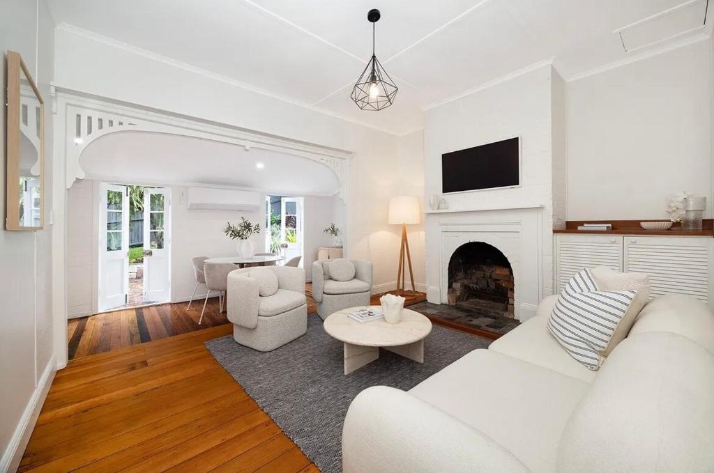 Elle comprend un salon doté d'un mobilier blanc et d'une cheminée. dans l'établissement Historic CBD Miner's Cottage, à Brisbane