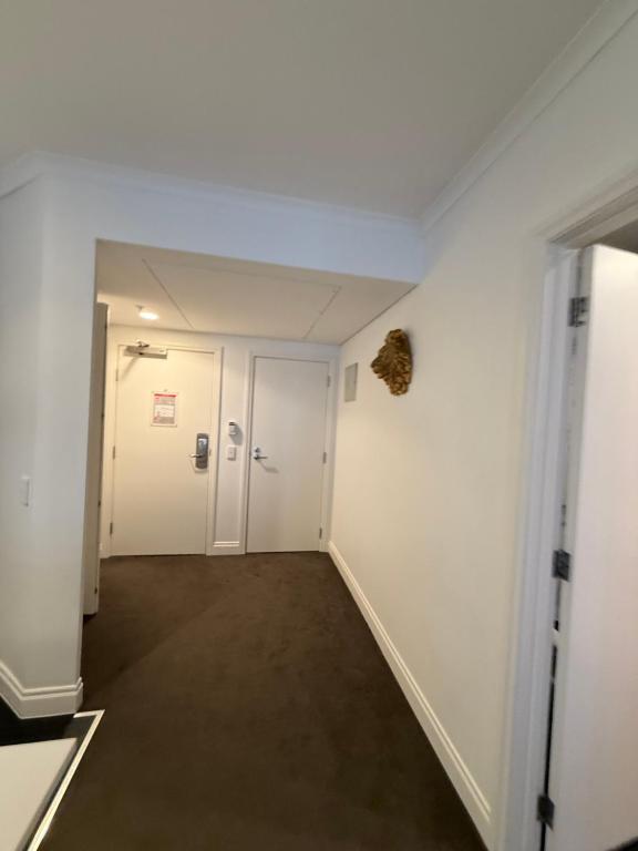 a hallway with white walls and a room with a door at Citylife getaway Pool Gym SKB in Auckland