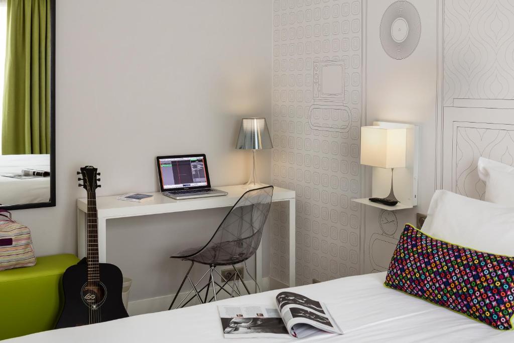 a bedroom with a bed with a laptop and a desk at Hôtel Paris Vaugirard in Paris