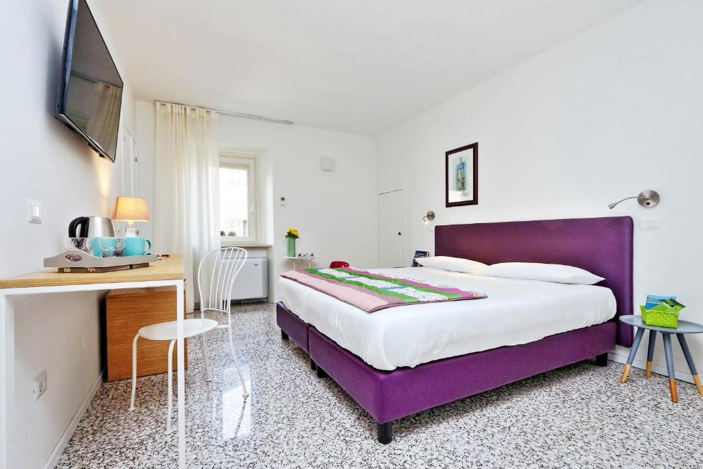 una camera con letto viola e scrivania di Guest House Viaroma a San Severino Marche
