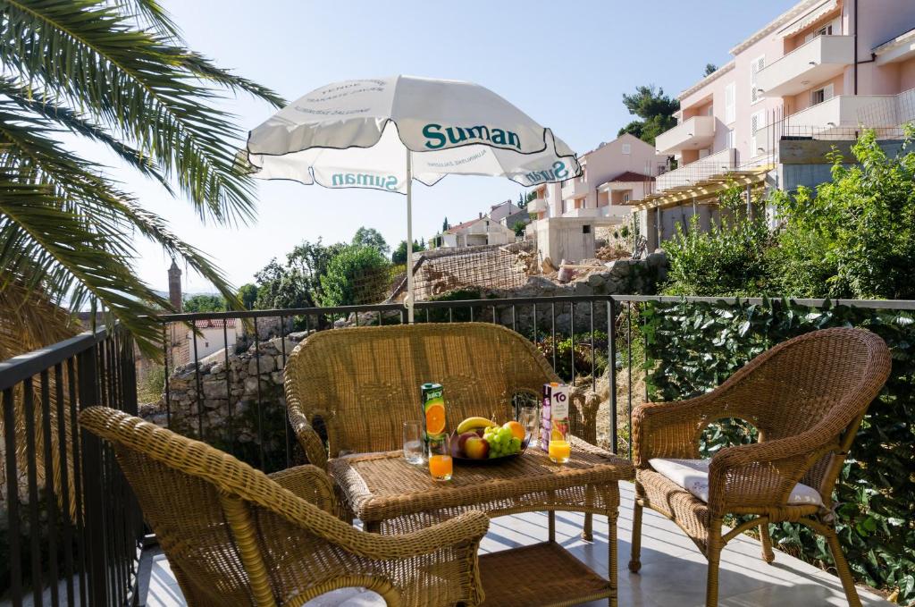un tavolo e sedie su un balcone con ombrellone di Apartment Palma a Dubrovnik