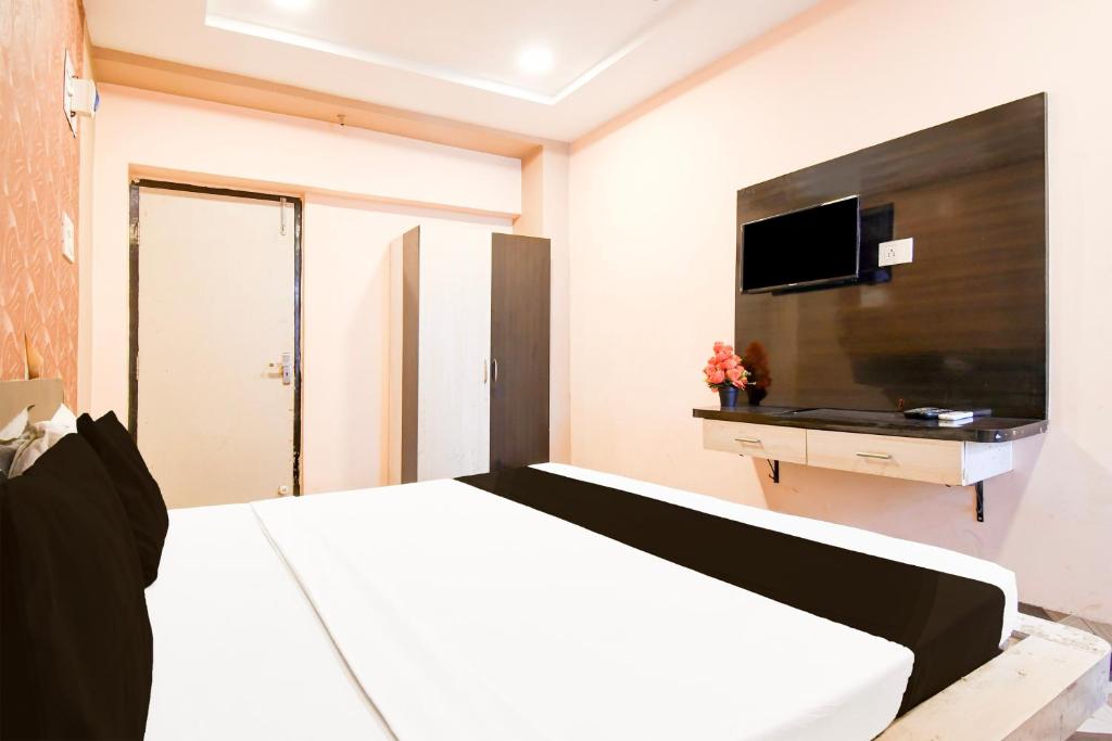 Un dormitorio con una cama y un televisor en una pared. en Hotel O Mrinmoyi Guest House, en Kulti