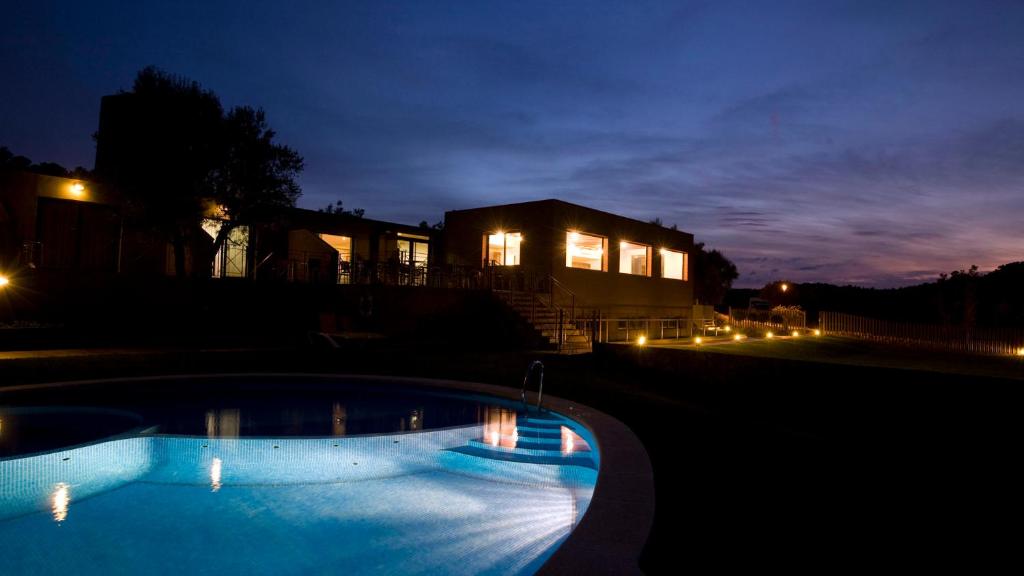 una piscina por la noche con una casa en el fondo en Hotel Vilar Riu de Baix, en Flix