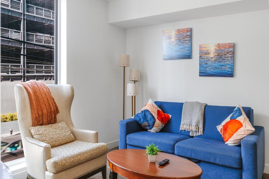 Una sala de estar con un sofá azul y una silla. en StaysPro - luxury Apartments minutes to everything Los Angeles, en Los Ángeles