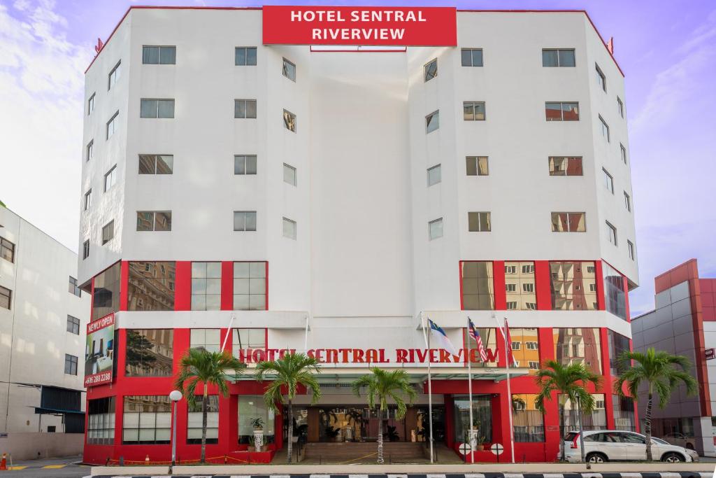 a white hotel with a red sign on top of it at Hotel Sentral Riverview Melaka in Malacca