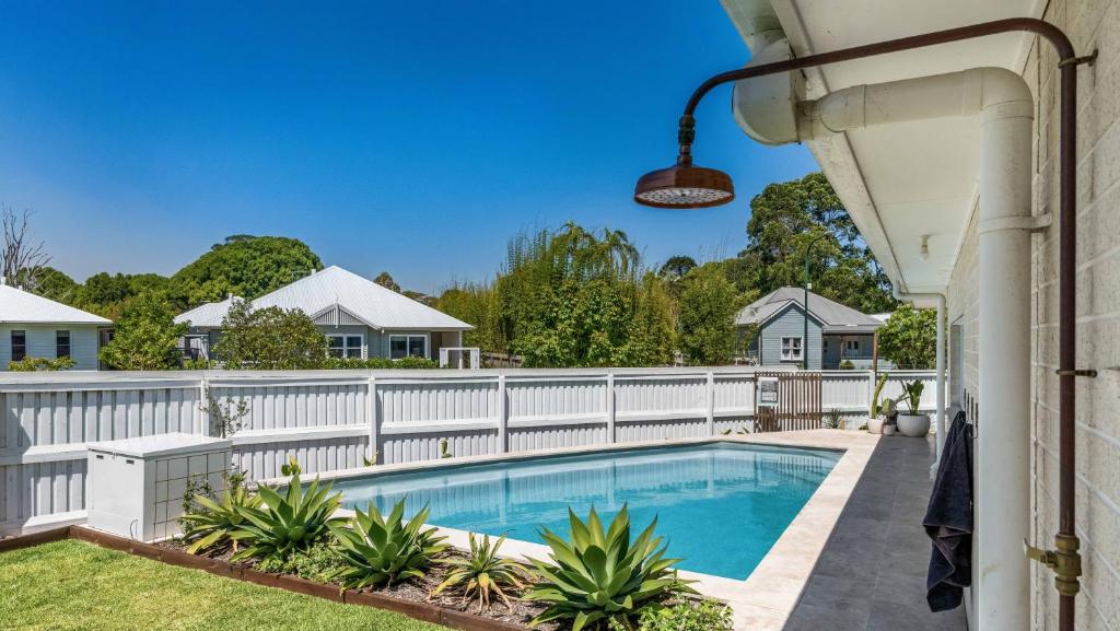 una recinzione bianca attorno a una piscina con una staccionata bianca di Bangalow Breeze - Lovely Pool - Walk to Centre a Bangalow